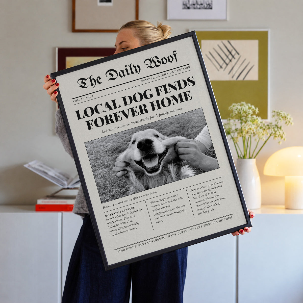 Gotcha Day custom pet newspaper print in a black frame, held up in a living room, with an example photo