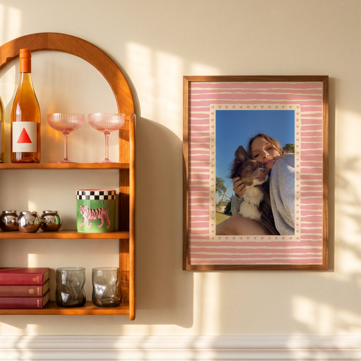 Hearts custom pet photo print in Blush Pink, in a wooden frame on a sunlit wall beside a shelf, with an example photo